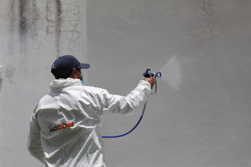 Persona usando equipo de pintura airless en un muro blanco